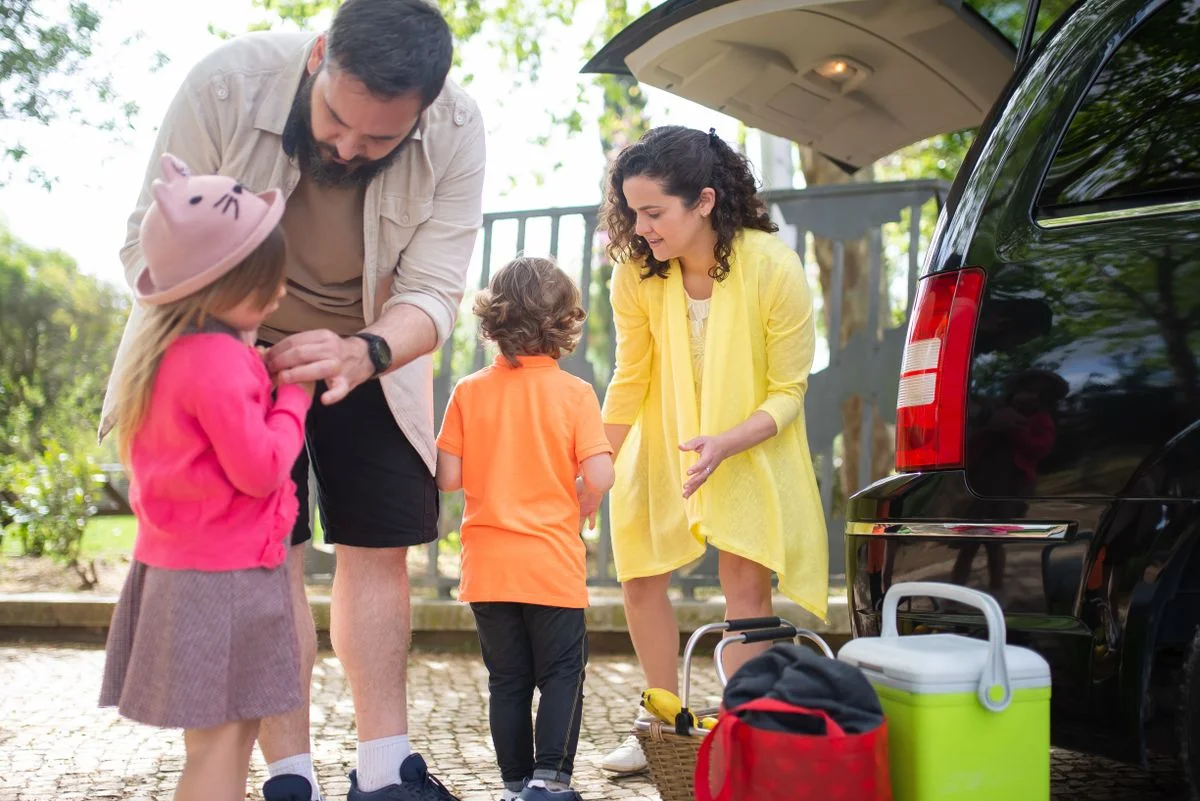 A family preparing for a journey beside their car